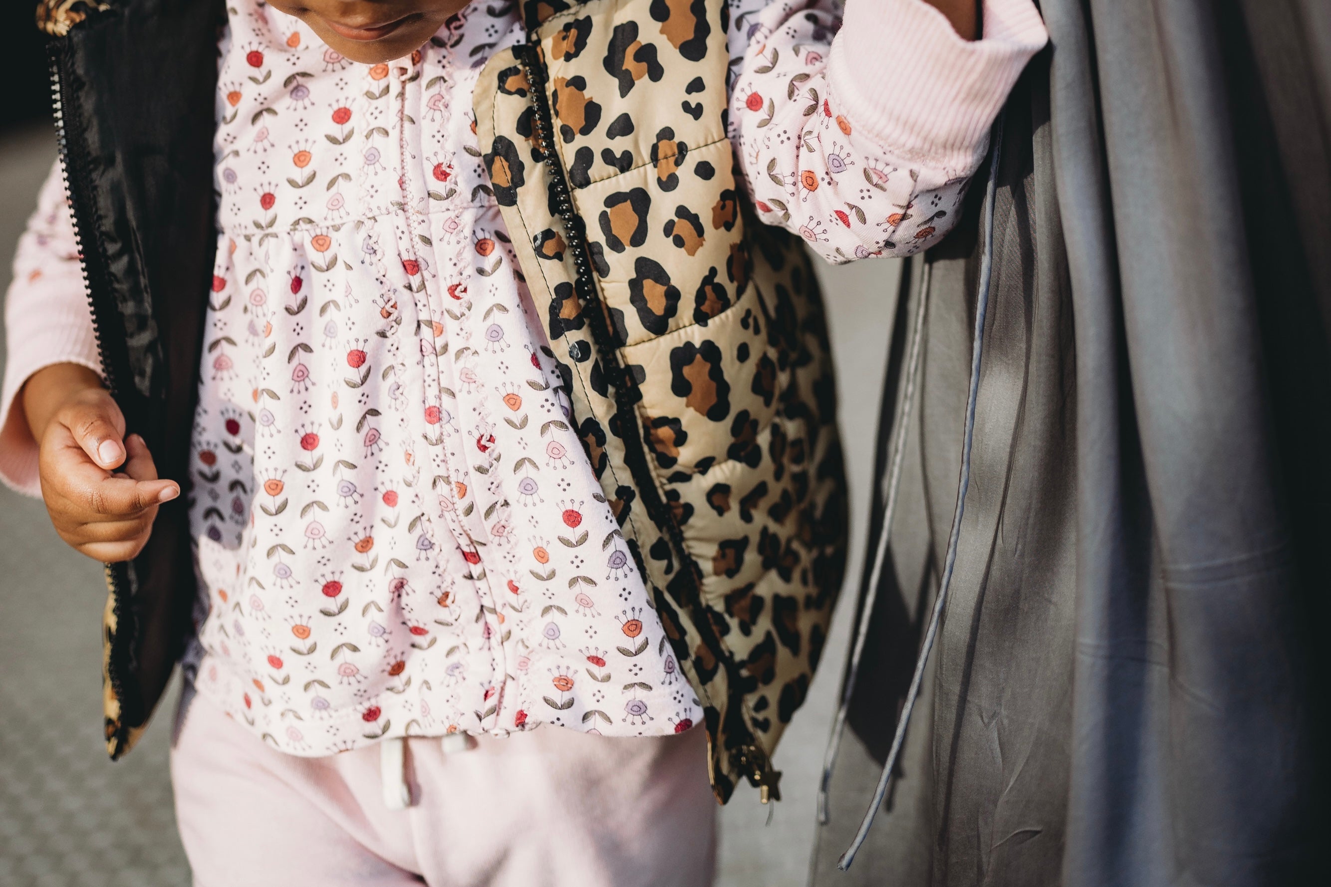 Person wearing a white floral blouse and leopard print jacket with a blurred background
