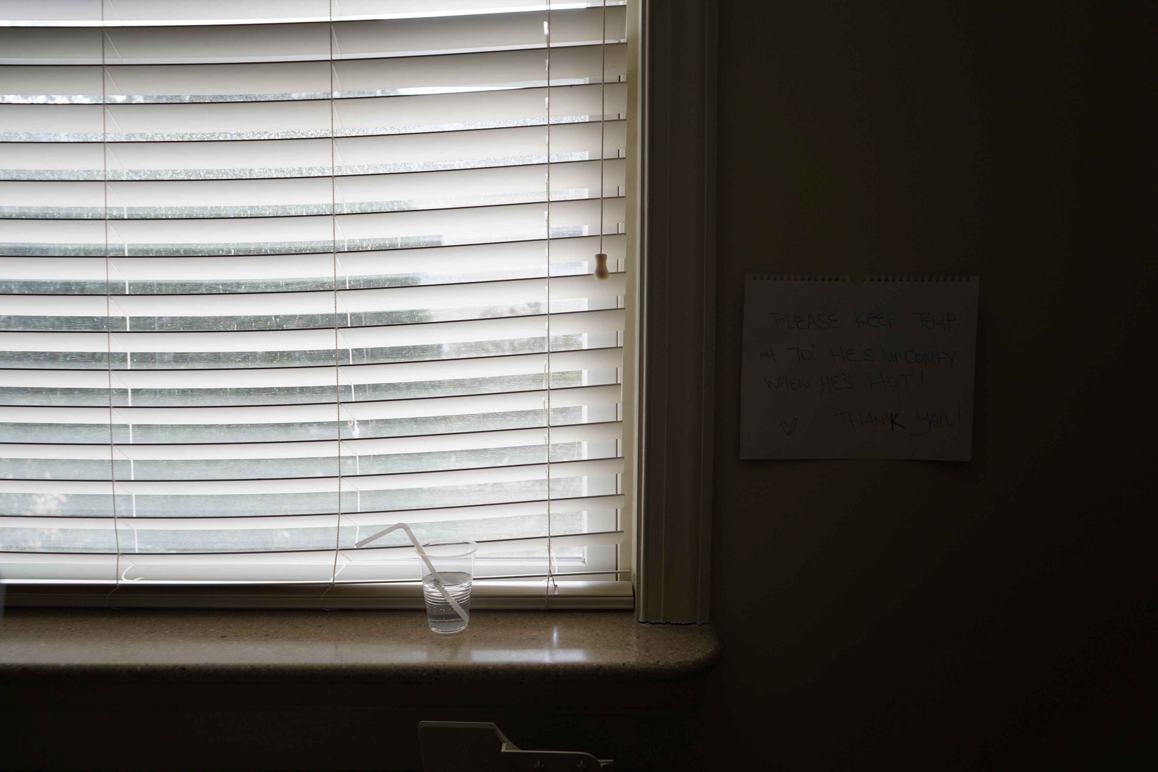Window with blinds partially open, showing a dark room beyond